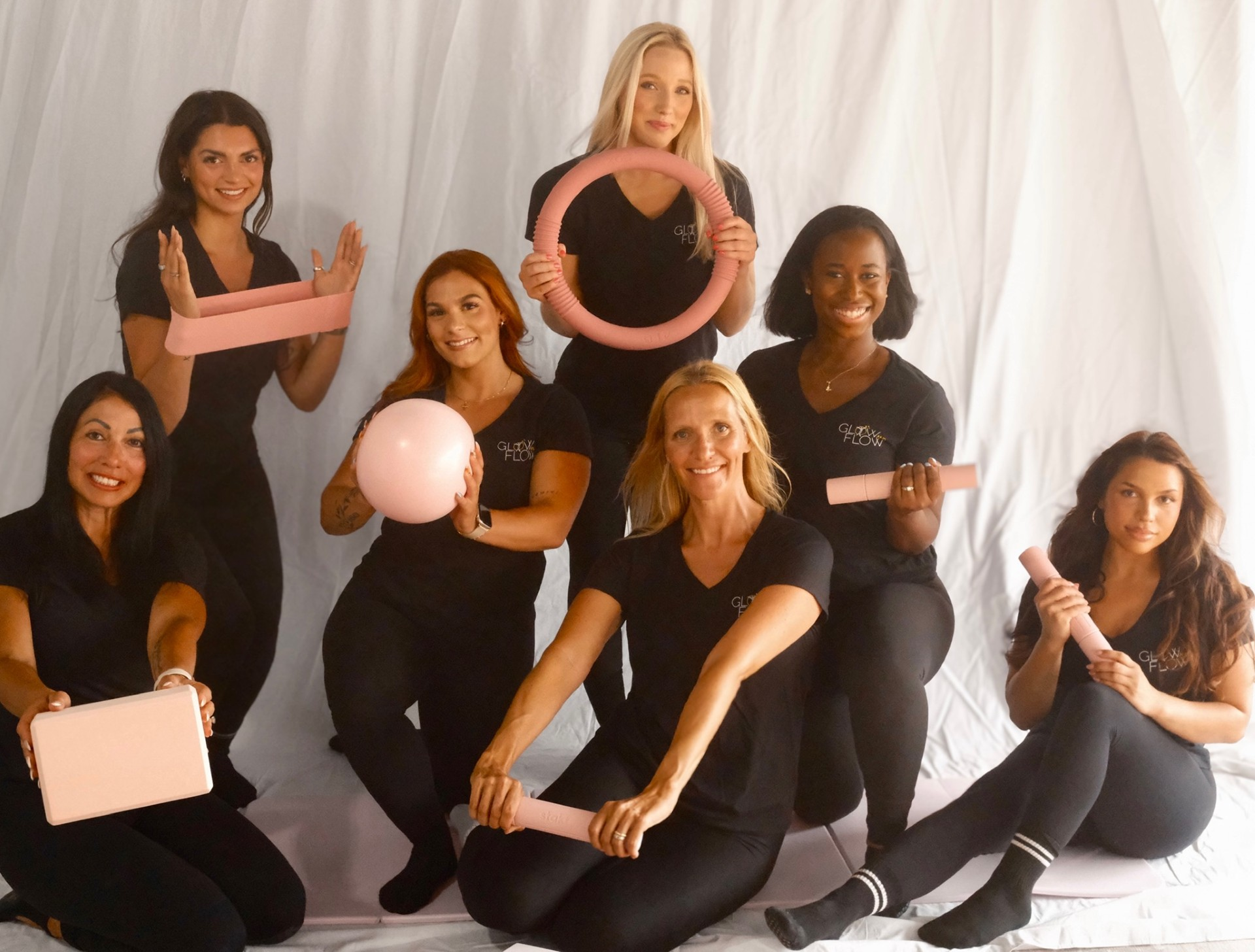 Glow and Flow instructor team posing with pink Pilates props