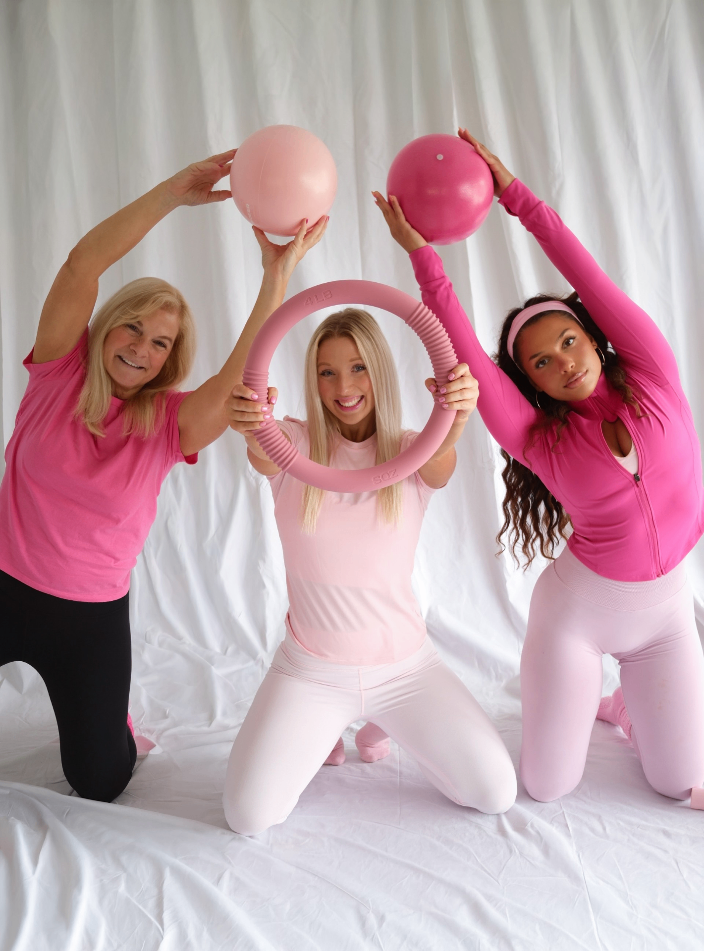 Three Glow and Flow instructors kneeling with Pilates balls and a ring