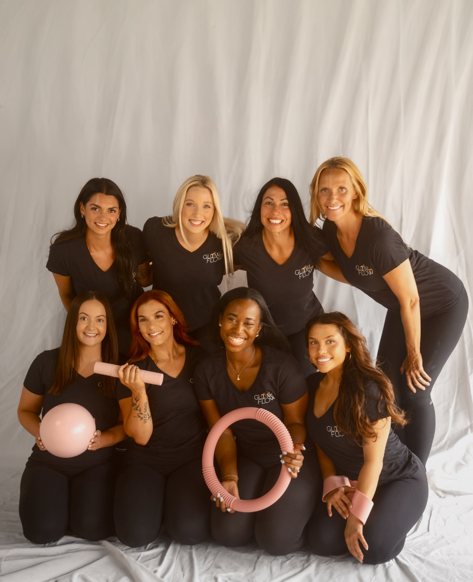 Glow and Flow instructors posing together with pink Pilates ball and ring