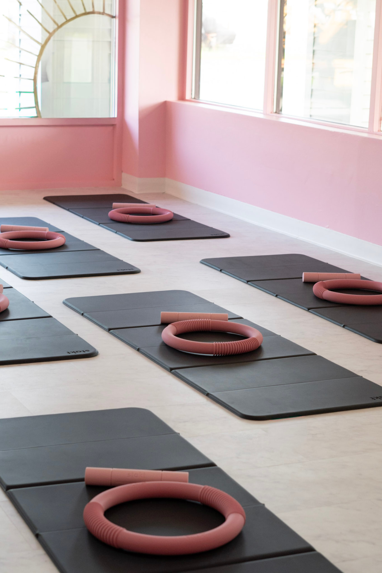 Mat Pilates studio with mats and pink Pilates rings set up by the windows