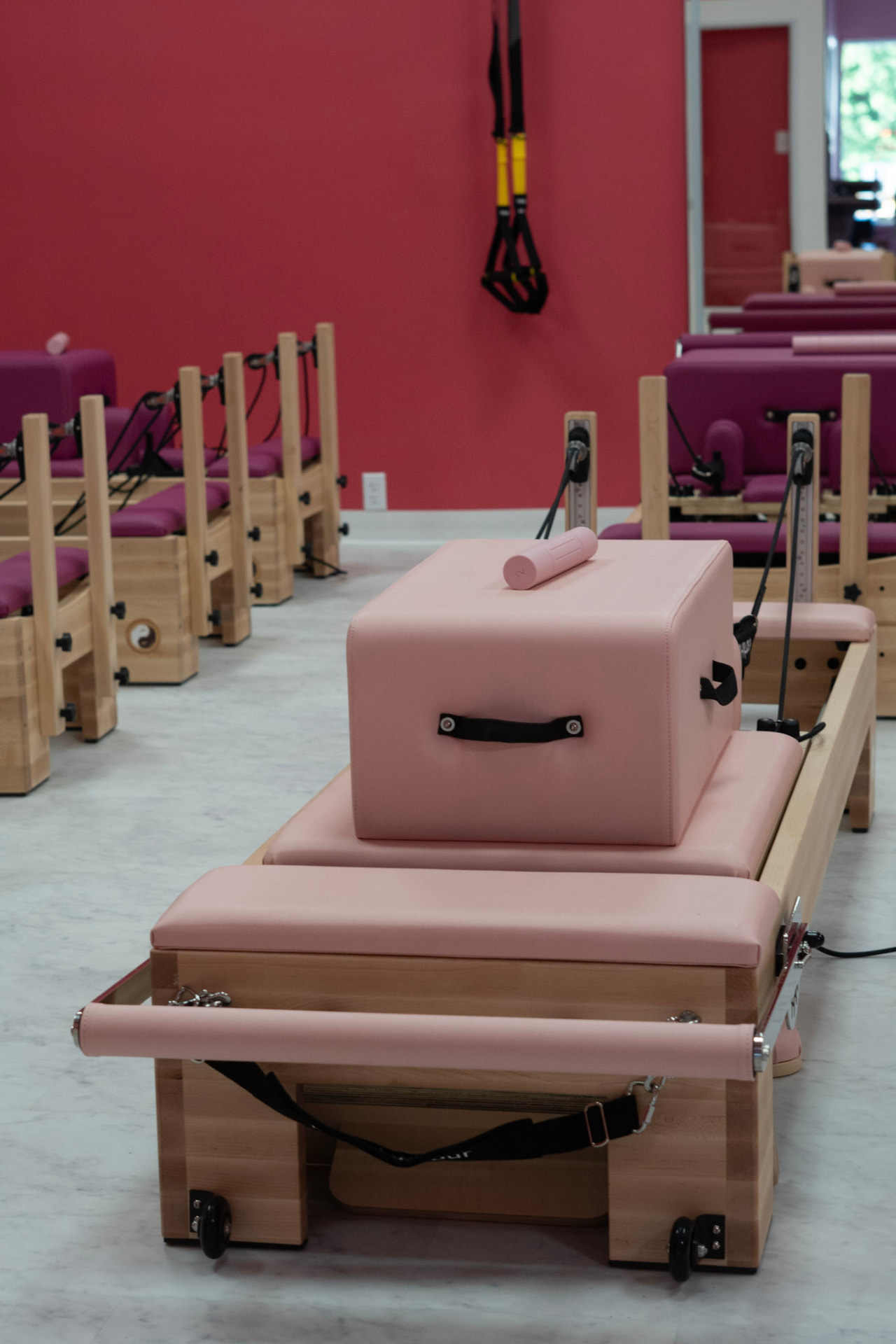 Pink reformer with jump box and roll-down bar in the Glow and Flow studio